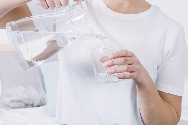 crop-woman-bed-pouring-water